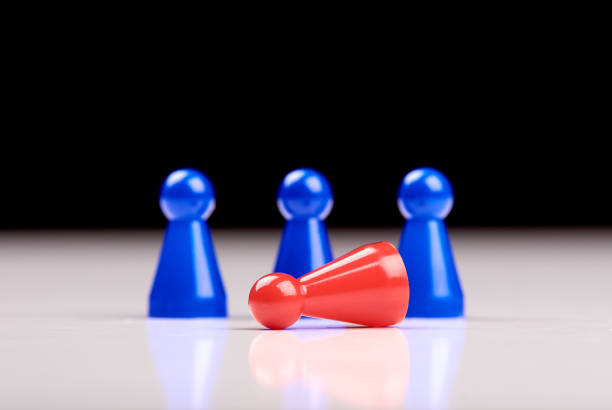 istock Standing three blue game pieces as winner and lying red figurine as loser on white table top with black background. Space for your text. 1154087406