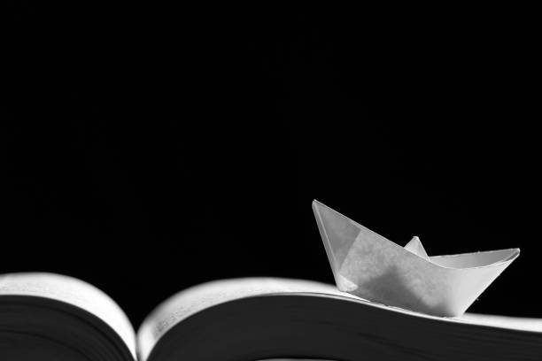 istock Paper boat on the opened book 1154090280