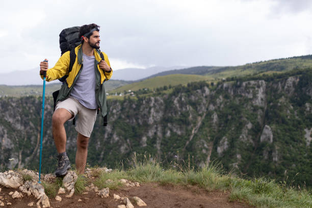 istock Young man traveling with backpack hiking in mountains 1154090366