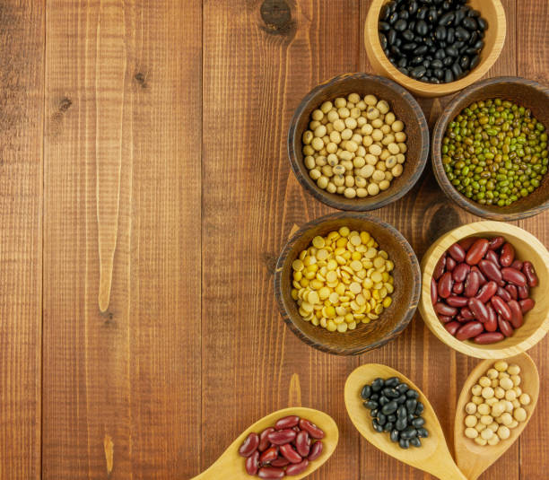 Flat lay,top view assorted beans including red bean,soybeans,black beans,mung beans on brown,beige wooden background with copy space