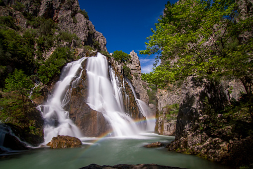 Low-angle view of the beautiful powerful waterfall hidden in the mountains during summertime in Scandinavia