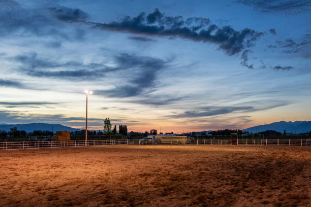 Empty equestrian arena at sunset Floodlights illuminating an empty equestrian arena in the USA. corral photos stock pictures, royalty-free photos & images