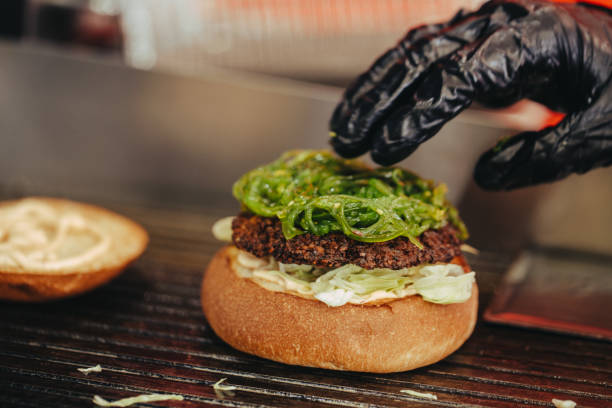 istock Cook preparing burger adding the sauce on the cream cheese. Three burgers. 1154100215