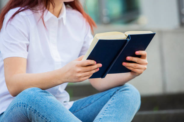 istock A confident student holding books over university building background. 1154100970