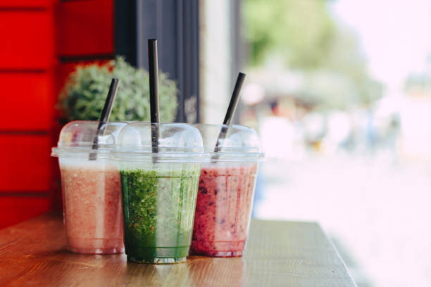 istock Sweet smoothie in plastic cups on wooden table 1154100975