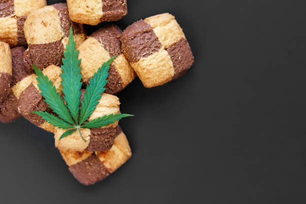 istock Hemp biscuits on a dark background with a green leaf of cannabis. Marijuana CBD dessert. Copy space. View from above 1154103949