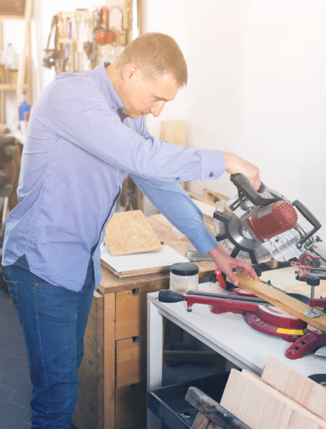 istock carpenter with  fret saw cutting wood plank at workshop 1154107574