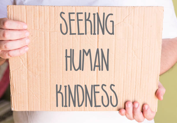 istock man holding Seeking Human Kindness Sign On Cardboard 1154112338