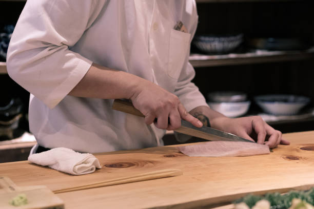 Chef preparing slicing raw fish for sushi at the counter-top, Omakase style Japanese traditional. Chef preparing slicing raw fish for sushi at the counter-top, Omakase style Japanese traditional. japanese chef stock pictures, royalty-free photos & images