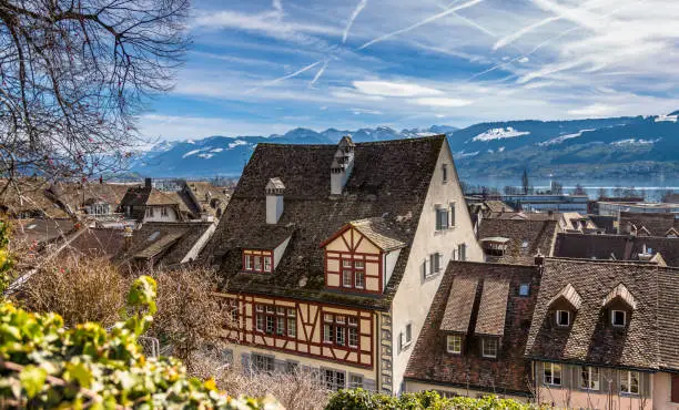 Roofs of the medieval old town of Rapperswil with the snow capped alpine ranges in the background, Sankt Gallen, Switzerland.