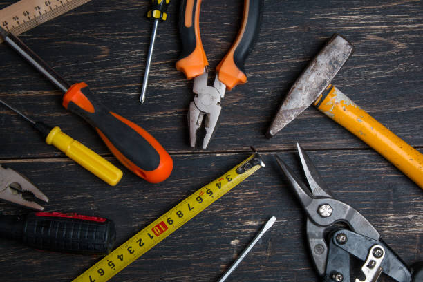 istock Old construction work tool on a wooden table. Pliers, tape measure, screwdriver, scissors and hammer. View from above. 1154127192