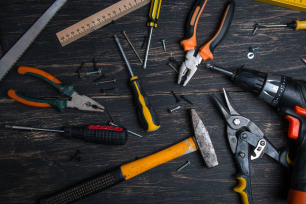 istock Old construction work tool on a wooden table. Pliers, tape measure, screwdriver, scissors and hammer. View from above. 1154127193
