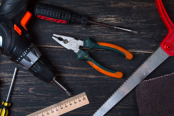 istock Old construction work tool on a wooden table. Pliers, tape measure, screwdriver, scissors and hammer. View from above. 1154127224