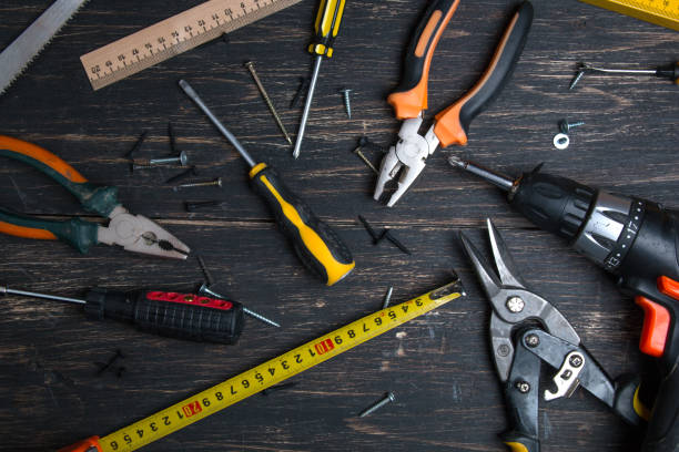 istock Old construction work tool on a wooden table. Pliers, tape measure, screwdriver, scissors and hammer. View from above. 1154127234