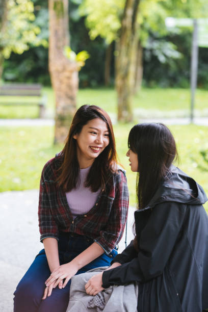 istock Two beautiful young woman resting on a bench in the park 1154128778