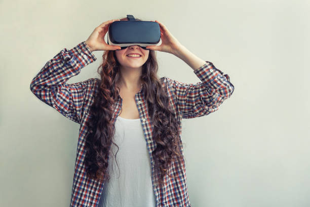 istock Smile young woman wearing using virtual reality VR glasses helmet headset on white background. Smartphone using with virtual reality goggles 1154129759