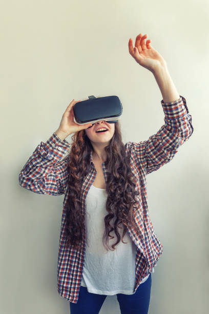 istock Smile young woman wearing using virtual reality VR glasses helmet headset on white background. Smartphone using with virtual reality goggles 1154130262