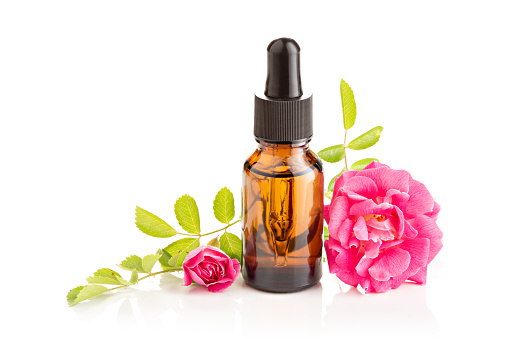 Rose essential oil in glass bottle with dropper on white background
