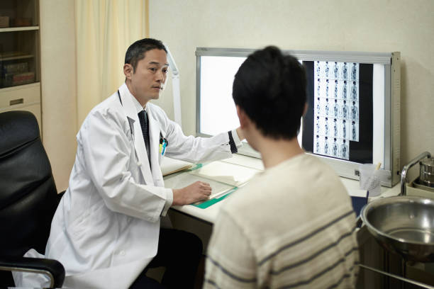 istock Male Japanese Doctor Explaining X-Ray Image to Patient 1154139250