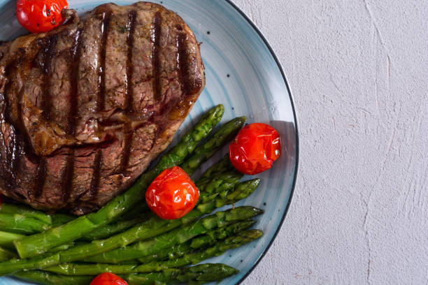 istock Grilled beef steak ribeye with cherry tomatoes and asparagus 1154139691