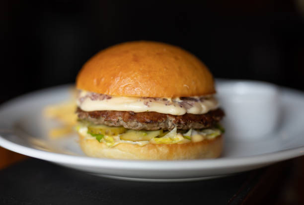 istock Burger in a plate on black background 1154142578