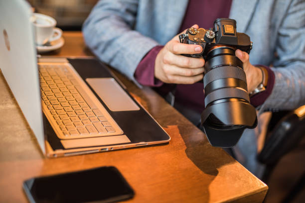 istock Hand close up of young man using camera while working in coffee shop. 1154145613
