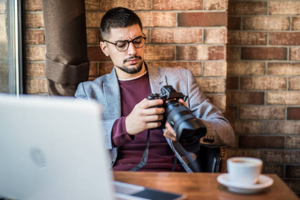 Young photographer checking photos  while working in coffee shop.