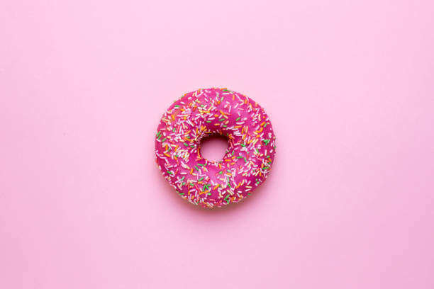 istock Sweet pink donut with multicolored sprinkles on a pink background flat lay 1154161924