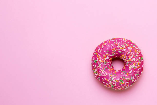 istock Sweet pink donut with multicolored sprinkles on a pink background flat lay 1154161935