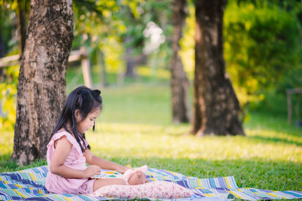 istock A little cute girl reading a book sitting under the tree 1154171875