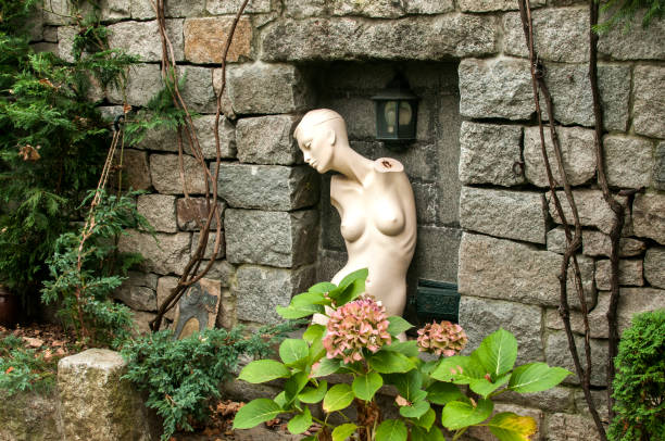 A female torso of mannequin in niche of stone house garden wall