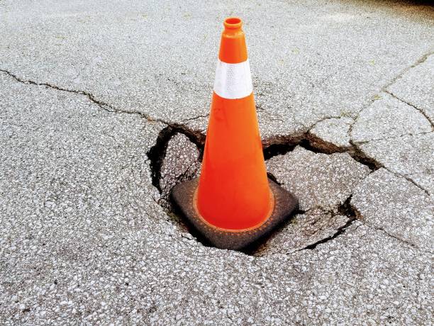 istock Sinkhole on an asphalt with an orange traffic cone 1154197888