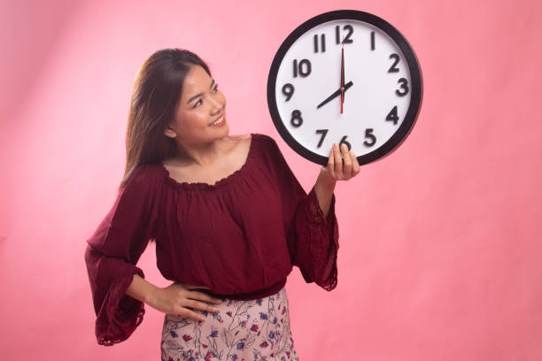 istock Young Asian woman with a clock. 1154199896