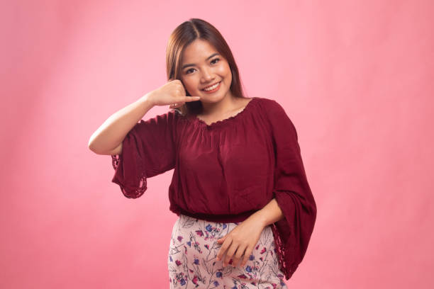 istock Young Asian woman show with phone gesture. 1154201807