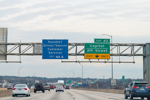 Harrisburg, USA - April 6, 2018: Exit sign on highway 83 north in Pennsylvania with cars traffic on cloudy day for Capitol and Penndot