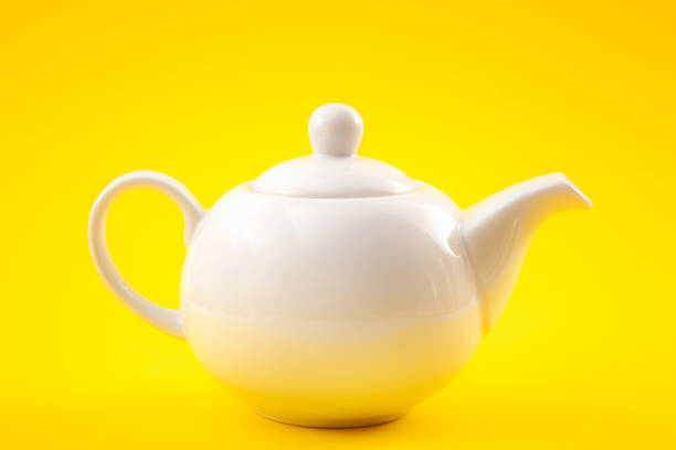 White porcelain tea pot, china pot or tea kettle isolated on yellow background