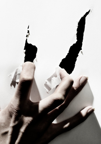 female hand tearing paper with nails