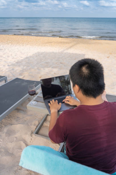 istock Asian man working with laptop by the beautiful beach 1154258584
