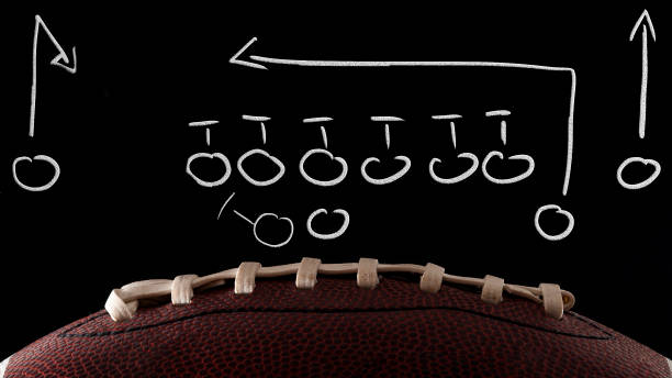 American football tactics scheme, sports coaching and offensive play concept with a ball in front of a blackboard with a game plan drawing done by the coach with dramatic lights American football tactics scheme, sports coaching and offensive play concept with a ball in front of a blackboard with a game plan drawing done by the coach with dramatic lights offensive line stock pictures, royalty-free photos & images