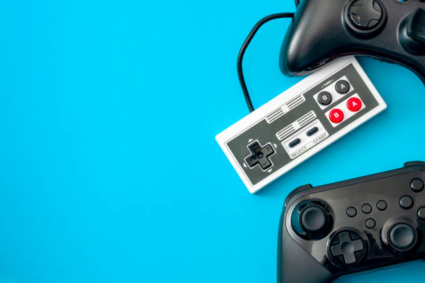 tema concettuale per giochi per computer e console di gioco con controller di videogiochi isolati su sfondo blu con copyspace - retro theme foto e immagini stock