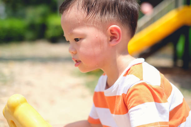 cute little asian 2 - 3 years old toddler boy child sweating during having fun playing, exercising outdoor at playground, heat stroke concept - 2 3 years fotos imagens e fotografias de stock