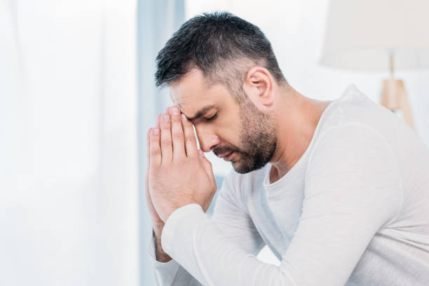 istock handsome bearded man with eyes closed doing please gesture and praying at home 1154319688