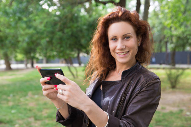 istock Smiling pretty lady browsing on smartphone in city park 1154319946