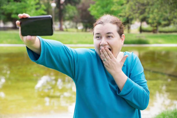 istock Amazed plus sized woman shooting herself in park 1154320053