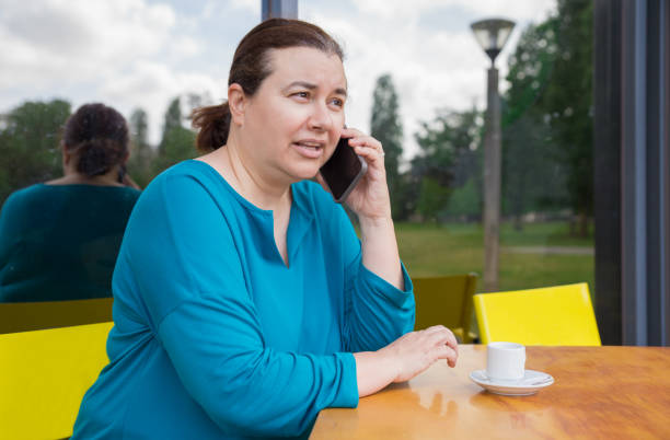 femme pensive sérieuse appelant sur le téléphone portable - overweight women serious people photos et images de collection