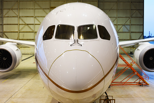 Front of a white 787 dreamliner aircraft in a hangar
