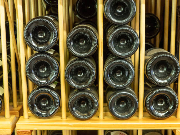 butelki czerwonego wina w stojaku na wino z końcami skierowanymi w sklepie - wine cellar liquor store wine rack zdjęcia i obrazy z banku zdjęć