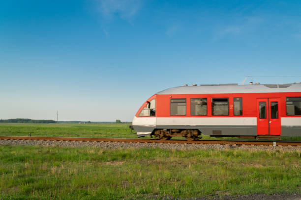 Fast moving train on tracks surrounded by summer meadows