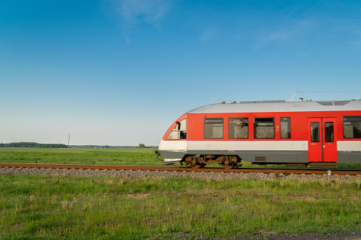 Fast moving train on tracks surrounded by summer meadows