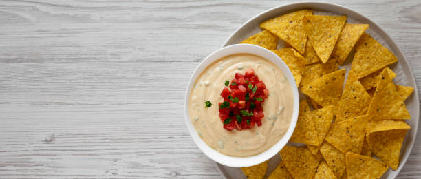 Homemade cheesy dip in a bowl, yellow tortilla chips, overhead view. Top view, from above, flat lay. Copy space. Homemade cheesy dip in a bowl, yellow tortilla chips, overhead view. Top view, from above, flat lay. Copy space. cheese dip stock pictures, royalty-free photos & images